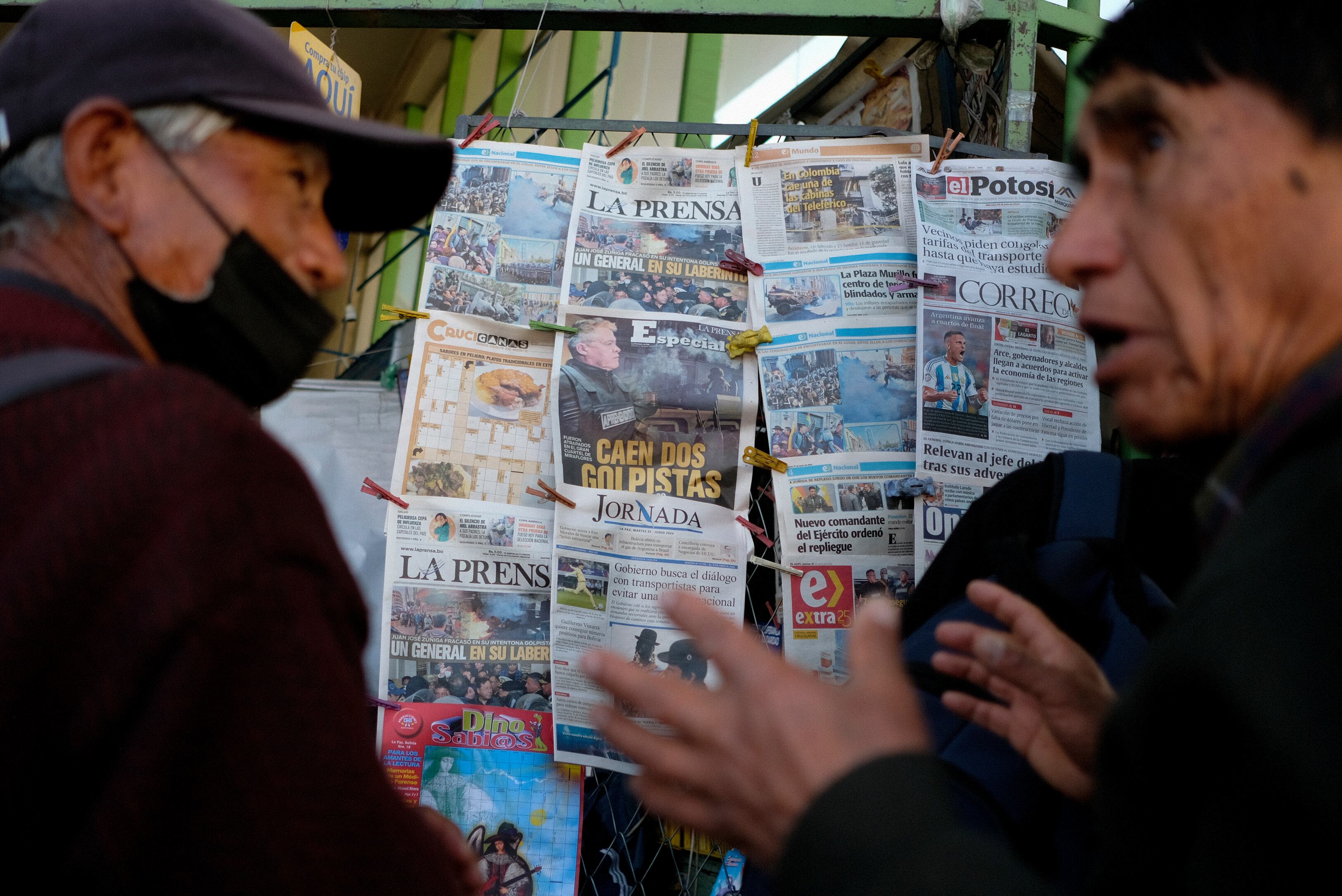 Hombres conversan frente a un quiosco de periódicos en La Paz, Bolivia, el jueves 27 de junio de 2024. (AP Foto/Carlos Sánchez)