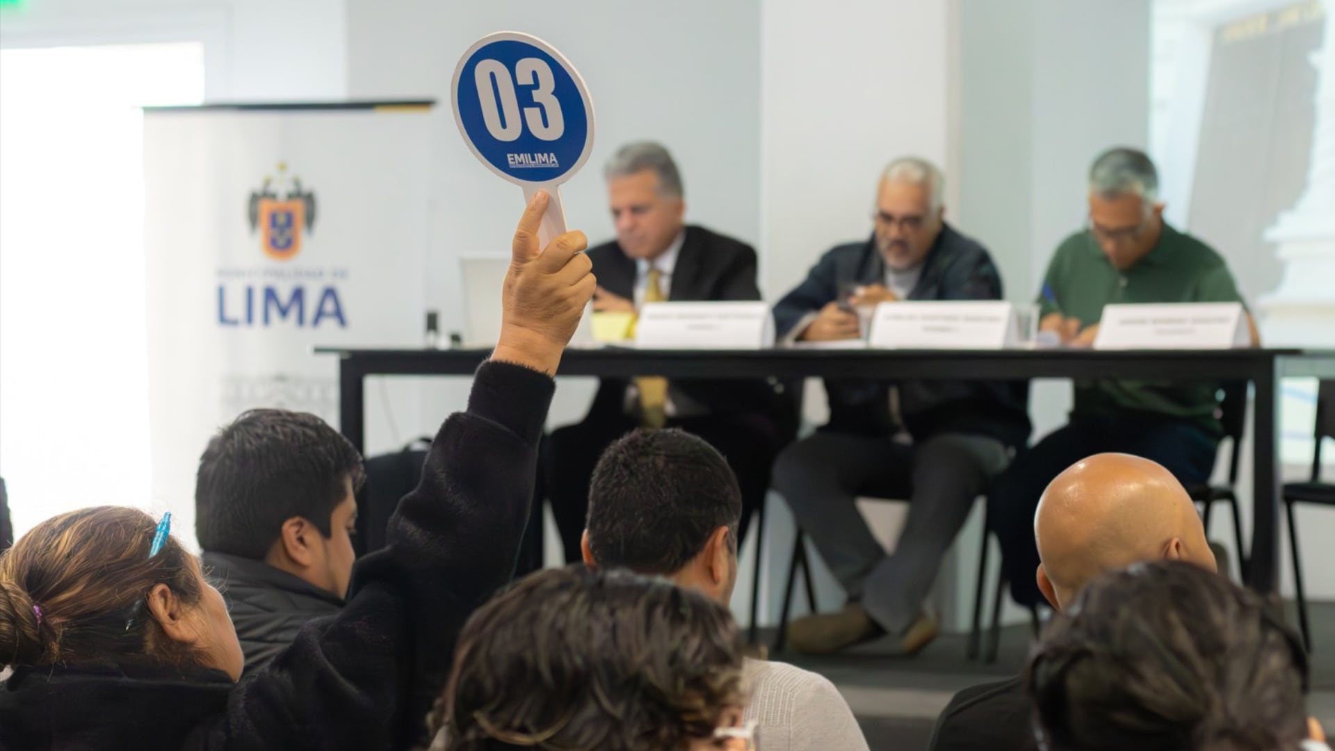 Una asistente alza una paleta de puja durante una subasta pública organizada por la Empresa Municipal Inmobiliaria de Lima.