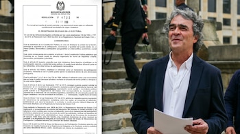 Un hombre de cabello rizado gris, con camisa blanca y blazer oscuro, sostiene papeles mientras mira a la derecha, con un documento oficial parcialmente visible a la izquierda.