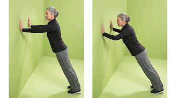 Una mujer con ropa deportiva y el cabello recogido apoya sus manos en una pared verde en dos secuencias de flexión de brazos.