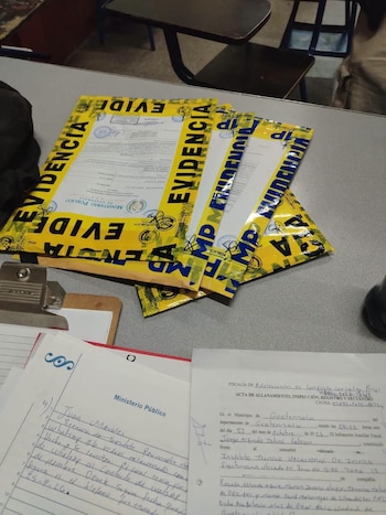 Bolsas amarillas con la palabra evidencia y actas judiciales impresas y manuscritas sobre un escritorio