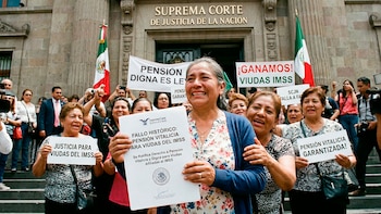 Un grupo de mujeres, algunas con lágrimas de alegría, celebran frente al edificio de la Suprema Corte, sosteniendo pancartas y un documento oficial