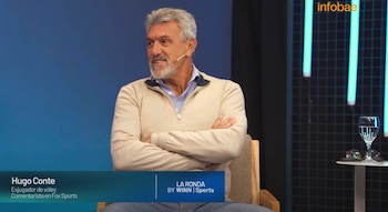 Hombre canoso y barbudo en suéter beige, sentado con los brazos cruzados, con micrófono. Texto inferior identifica a Hugo Conte en La Ronda 4. Fondo con luces de neón