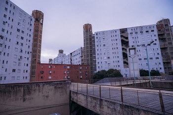 Edificios de departamentos de color blanco y rojo con torres altas de hormigón, pasarelas con barandillas y un cielo gris al fondo