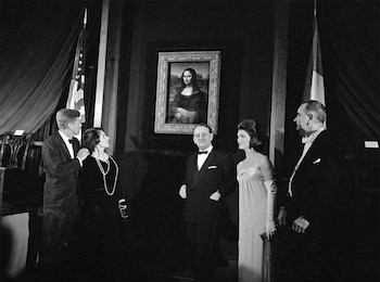 Cinco personas en vestimenta de gala miran el cuadro de la Mona Lisa en una galería de arte con la bandera de Estados Unidos y una bandera francesa