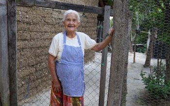 Dos mujeres mayores en sillas de ruedas se encuentran sentadas en primer plano junto a otros adultos al fondo de la habitación