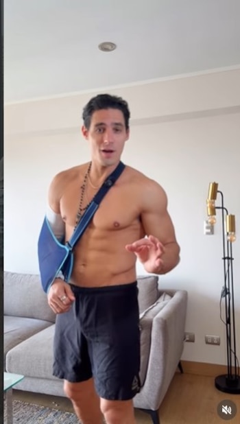 Facundo Gonzalez, sin camiseta y en shorts negros, con un cabestrillo azul en el brazo izquierdo, gesticula mientras habla en una sala de estar