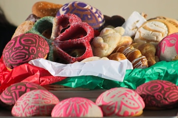 Galletas decoradas con figuras de colores, conchas y otros panes dulces colocados sobre papel de china rojo y verde