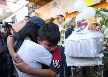 People embrace during the funeral