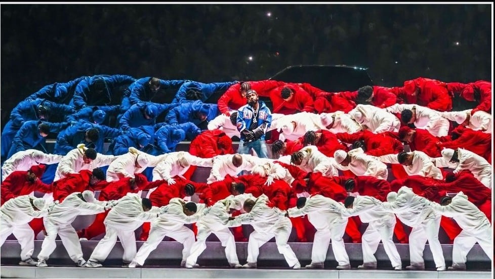 El rapero Kendrick Lamar realiza su actuación en el espectáculo de medio tiempo del Super Bowl rodeado de bailarines vestidos de azul, rojo y blanco en una fotografía de Jenn Devereaux