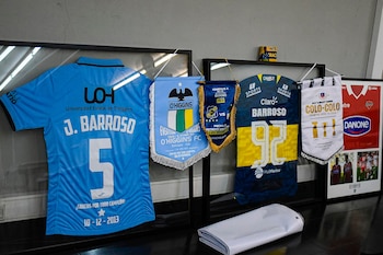 Dos camisetas de fútbol enmarcadas, una celeste con "J. Barroso" y "5", otra azul y amarilla con "Barroso" y "92". Tres banderines y una camiseta roja enmarcada