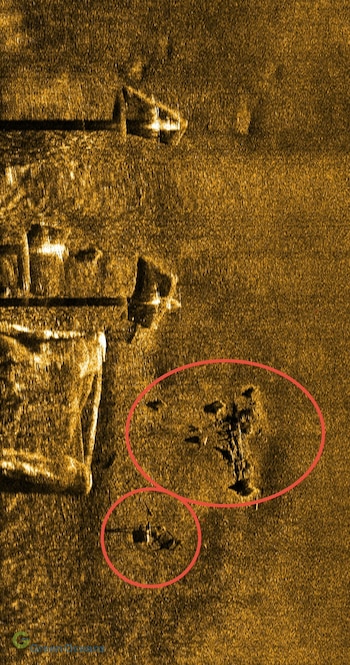 Imagen en tonos dorados de un sonar que muestra el fondo marino y dos zonas destacadas con círculos rojos