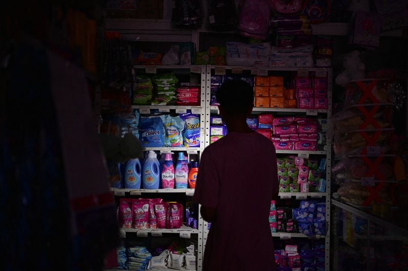Un hombre utiliza la luz de su teléfono móvil en una tienda sin electricidad durante un apagón que afecta a Caracas y otras regiones del país, en Caracas, Venezuela. 30 de agosto 2024. REUTERS/Gaby Oraa - RC2MQ9AFBTYP
