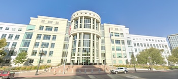Edificio judicial de varios pisos con fachada blanca, columnas centrales, banderas de Estados Unidos y una patrulla estacionada al frente