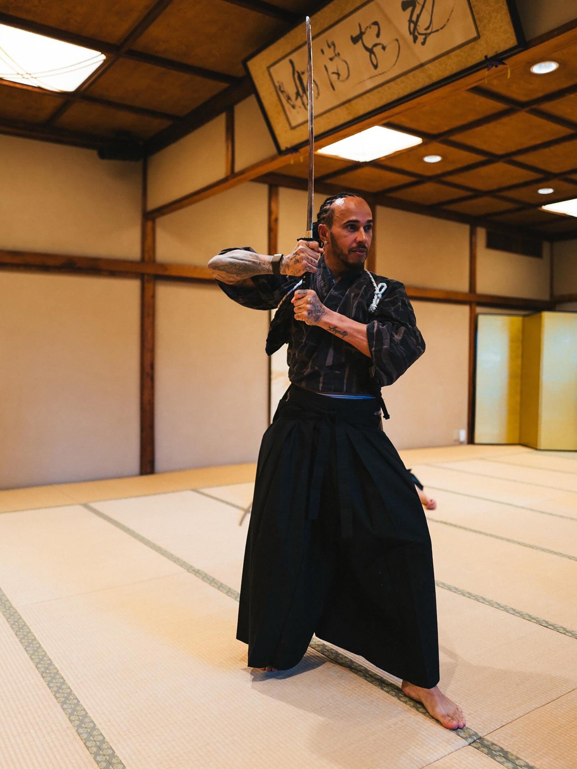 El piloto de Fórmula 1 Lewis Hamilton muestra su concentración mientras practica un arte marcial japonés con una katana en un dojo tradicional.