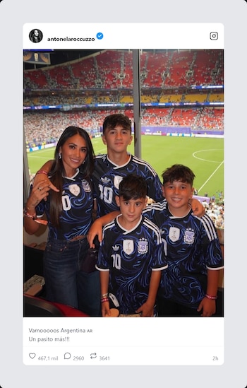Antonela Roccuzzo y tres niños en un palco de estadio. Todos visten camisetas de la selección argentina. Al fondo, gradas con público