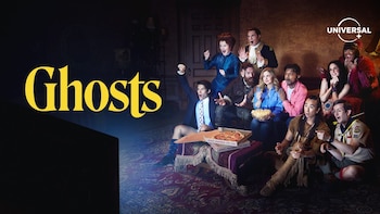 Diez personas con disfraces variados reaccionan con sorpresa y asombro mientras miran una pantalla de televisión en una habitación oscura. Pizza y palomitas