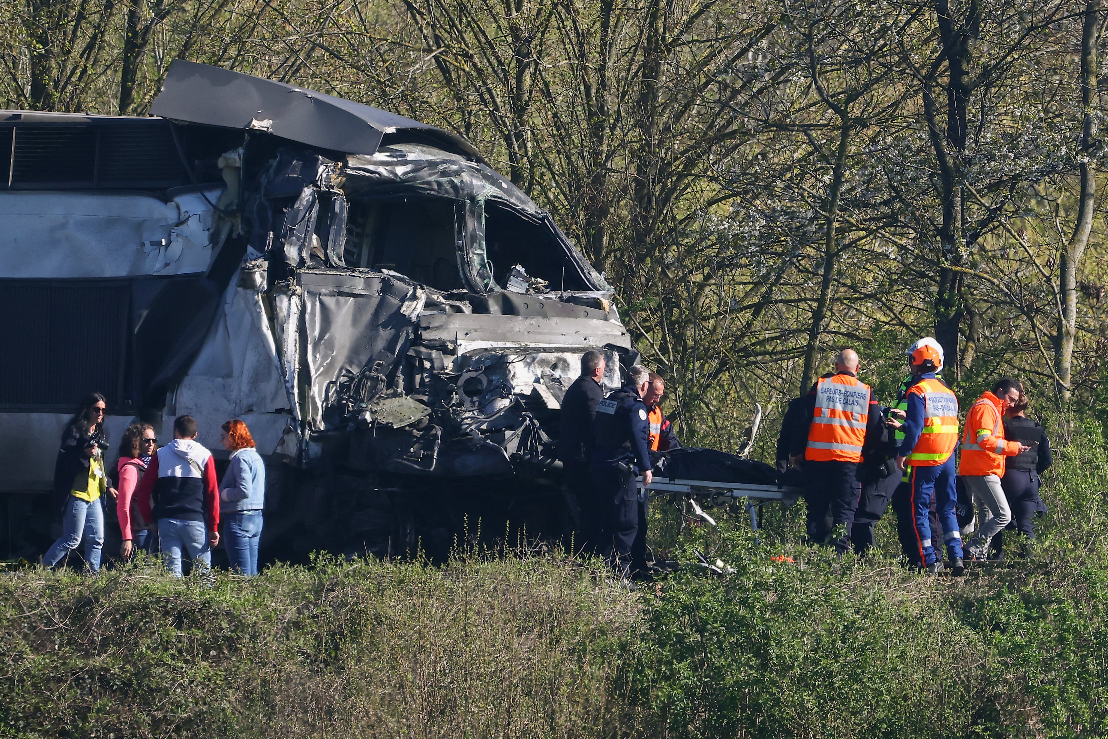 Bomberos y policías trasladan a una persona de entre los restos de un tren TGV tras su colisión con un camión en un paso a nivel entre Béthune y Lens, en Bully-les-Mines, en la región de Pas-de-Calais, al norte de Francia (Foto de Sameer AL-DOUMY / AFP)