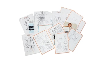 Pila de papeles con bocetos de moda, diseños de indumentaria y el logo de Chloé. Incluye una fotografía de mujer y algunos papeles con borde naranja