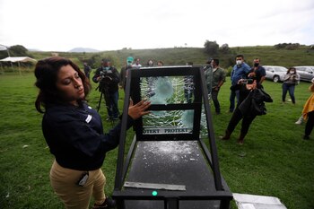 Una mujer, muestra los impactos de bala a una placa de vidrio blindado, hoy durante una prueba de balística del consejo nacional de la industria de la balística (CNB)en la Ciudad de México (México). EFE/Sáshenka Gutiérrez