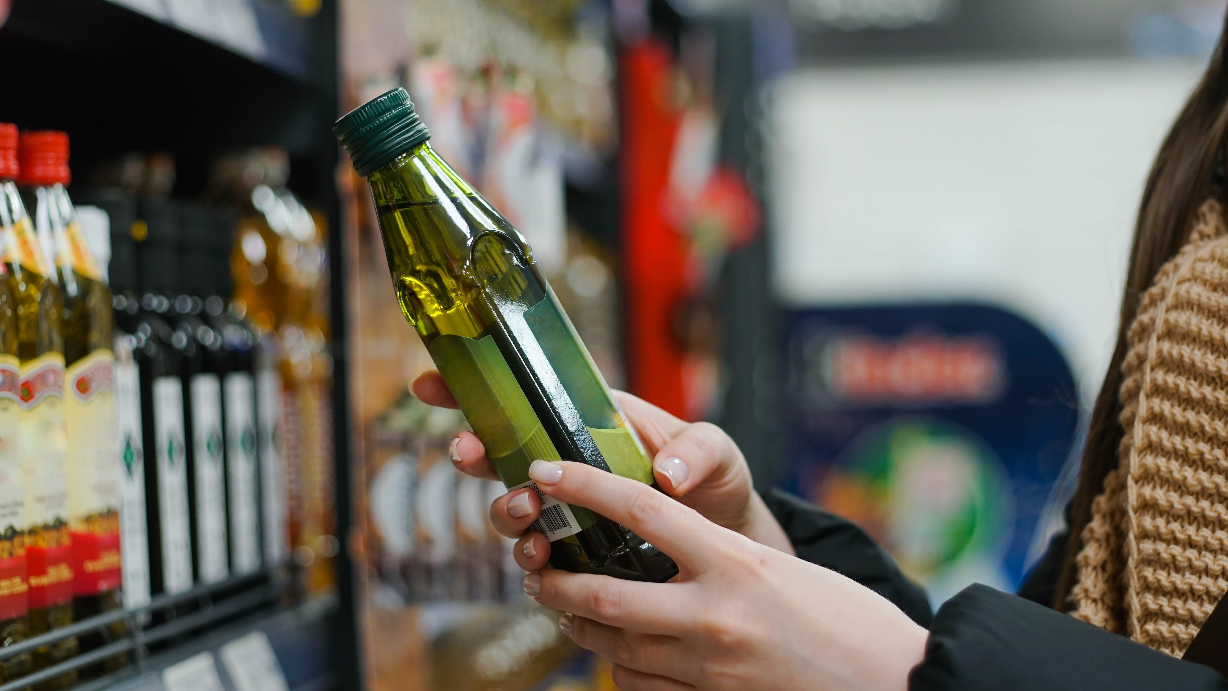 Una mujer sostiene una botella de aceite en un supermercado (Shutterstock)
