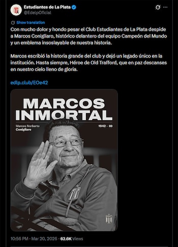 Retrato en blanco y negro de Marcos Conigliaro, un hombre con gafas sonriendo, mano derecha levantada. Viste una chaqueta con el escudo de Estudiantes