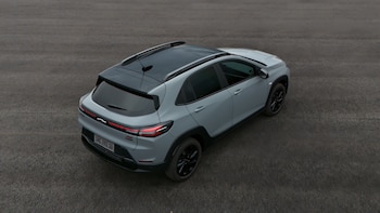 Primer plano de la rueda delantera izquierda de un Chevrolet Sonic gris claro, mostrando la llanta de aleación negra, el neumático Bridgestone y parte del guardabarros