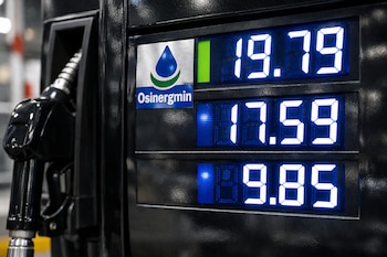 Pantalla digital de surtidor de combustible con precios 19.79, 17.59 y 9.85, y calcomanía con el logo de Osinergmin. Boquerel de combustible negro.
