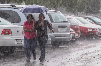 Personas caminan bajo la intensa lluvia en medio de la emergencia climática que afecta a República Dominicana, donde las precipitaciones han provocado desplazamientos y afectaciones en varias provincias. (Foto de cortesía)