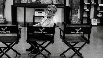 Fotografía en blanco y negro de Karina Duprez sentada de espaldas en una silla negra de director de Europacorp, mirando por encima del hombro