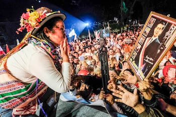 Keiko Fujimori, con sombrero floral y vestimenta tradicional, lanza un beso a una multitud de simpatizantes con manos alzadas y teléfonos. Un cartel de Alberto Fujimori es visible