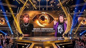 Escenario de televisión con luces de colores, confeti en el aire, una pantalla central con un ojo dorado y público abajo.
