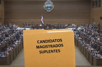 Primer plano de un folder con la frase 'CANDIDATOS MAGISTRADOS SUPLENTES' en letras negras, con el plenario de la Asamblea Legislativa de Costa Rica desenfocado al fondo.