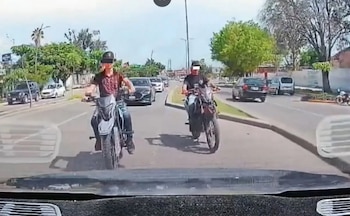 Un automóvil de plataforma digital circula por una avenida del centro de Chapala, Jalisco, seguido de cerca por varias motocicletas y un auto gris. Crédito: Especial