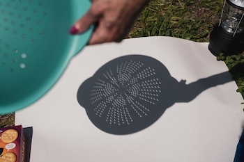 FILE Ñ Spectators use a colanderÕs holes to show the shadow of the solar eclipse at a viewing party at Big Muddy Brewing in Murphysboro, Ill., on Monday, April 8, 2024. If you plan to watch the solar eclipse, make sure your lenses offer enough protection. Alternatively, you can safely watch using household items. (Andrea Morales/The New York Times)