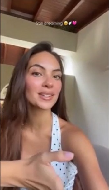 Natalie Vértiz, con cabello castaño largo y un top de lunares, sonríe a la cámara mientras gesticula levemente con una mano