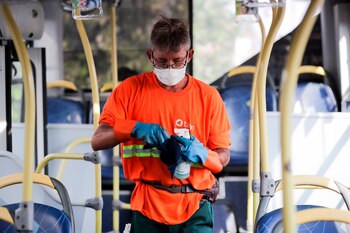 Un chofer higieniza un colectivo,