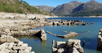 Al fondo unas montañas, se ve el agua de la presa y las estructuras caídas de las paredes.