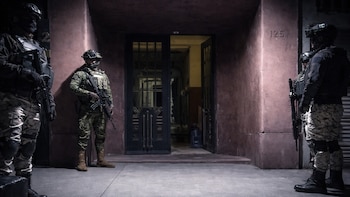 Cuatro agentes de la SSC CDMX con equipo táctico y armas de fuego se posicionan frente a la entrada abierta de un edificio con el número 125
