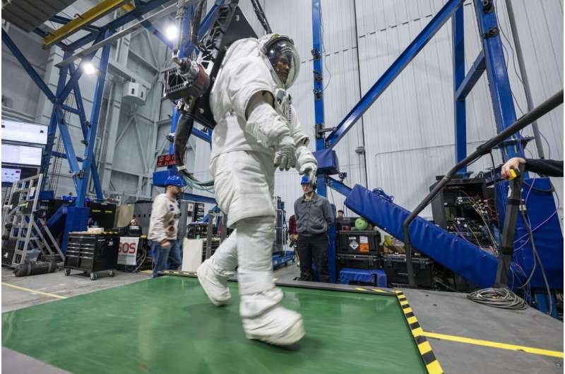 El astronauta de Artemis II, Victor Glover, camina en una cinta de correr con un traje espacial conectado al Sistema de Descarga de Gravedad de Respuesta Activa de la NASA en el Centro Espacial Johnson de la NASA. Glover simula una caminata sobre la superficie de un planeta con un traje adaptado a la gravedad lunar. Los astronautas de Artemis II completaron esta y otras tareas con el traje antes del lanzamiento de su misión y pocos días después del aterrizaje, lo que permitió a los investigadores evaluar la rapidez con la que los cuerpos de las tripulaciones se adaptan a una gravedad diferente tras el alunizaje. Los resultados ayudarán a los científicos a comprender mejor cuánto tiempo después del aterrizaje las tripulaciones pueden completar tareas cruciales para la misión en la superficie de la Luna o Marte (NASA/Robert Markowitz)