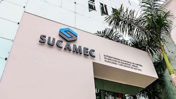 Vista exterior de la fachada de un edificio claro con el letrero y logotipo de la Sucamec junto a una planta de palmera