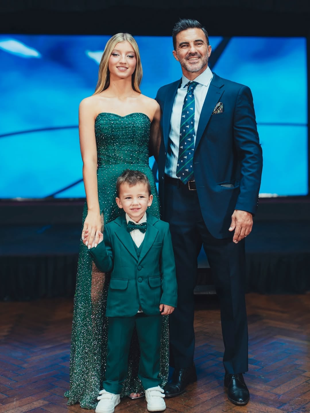 Fabián Cubero posa sonriente junto a su hija Allegra y su hijo Luca, quienes lucen elegantes atuendos para la fiesta de 15