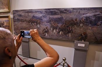 Una visitante toma una fotografía de una sección de un cuadro panorámico que representa la defensa de Sebastopol durante la guerra de Crimea del siglo XIX, la parte que se conservó aparte del panorama completo destruido por un ataque ucraniano, el jueves 11 de junio de 2026, en Sebastopol, Crimea. (Foto AP)