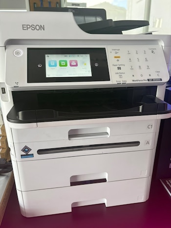 Impresora multifuncional blanca con panel de control, pantalla digital, teclado numérico y bandejas de papel frontales