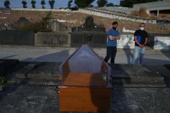 Dos personas observan un ataúd en el cementerio, en Brasil REUTERS/Pilar Olivares