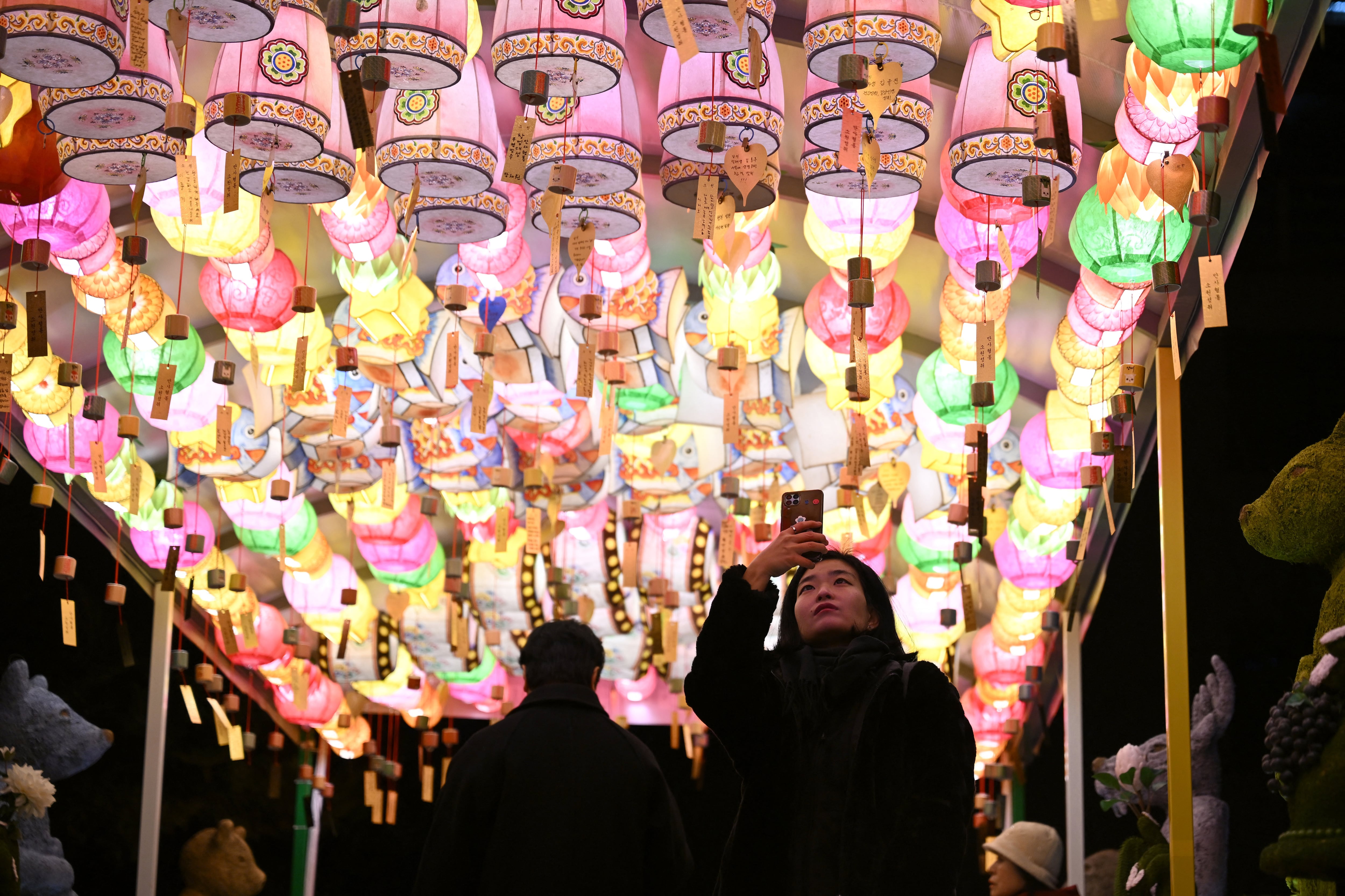 Una mujer se fotografía bajo linternas con deseos de Año Nuevo de seguidores budistas en el templo Jogyesa en el centro de Seúl. Seúl, 31 de diciembre de 2025. (Foto: Jung Yeon-je / AFP)