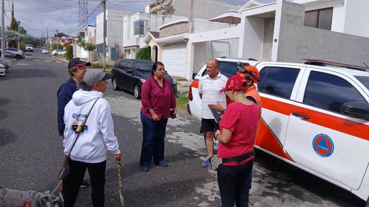 Personal de la Coordinadora Nacional para la Reducción de Desastres (CONRED) de Guatemala conversa con residentes en una calle urbana junto a un vehículo oficial. (Redes Sociales)