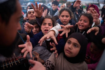 Familias desplazadas extienden las manos mientras esperan a recibir donativos de alimentos en un campamento después de huir de los bombardeos israelíes en el sur de Líbano, el jueves 9 de abril de 2026, en Beirut. (AP Foto/Emilio Morenatti)