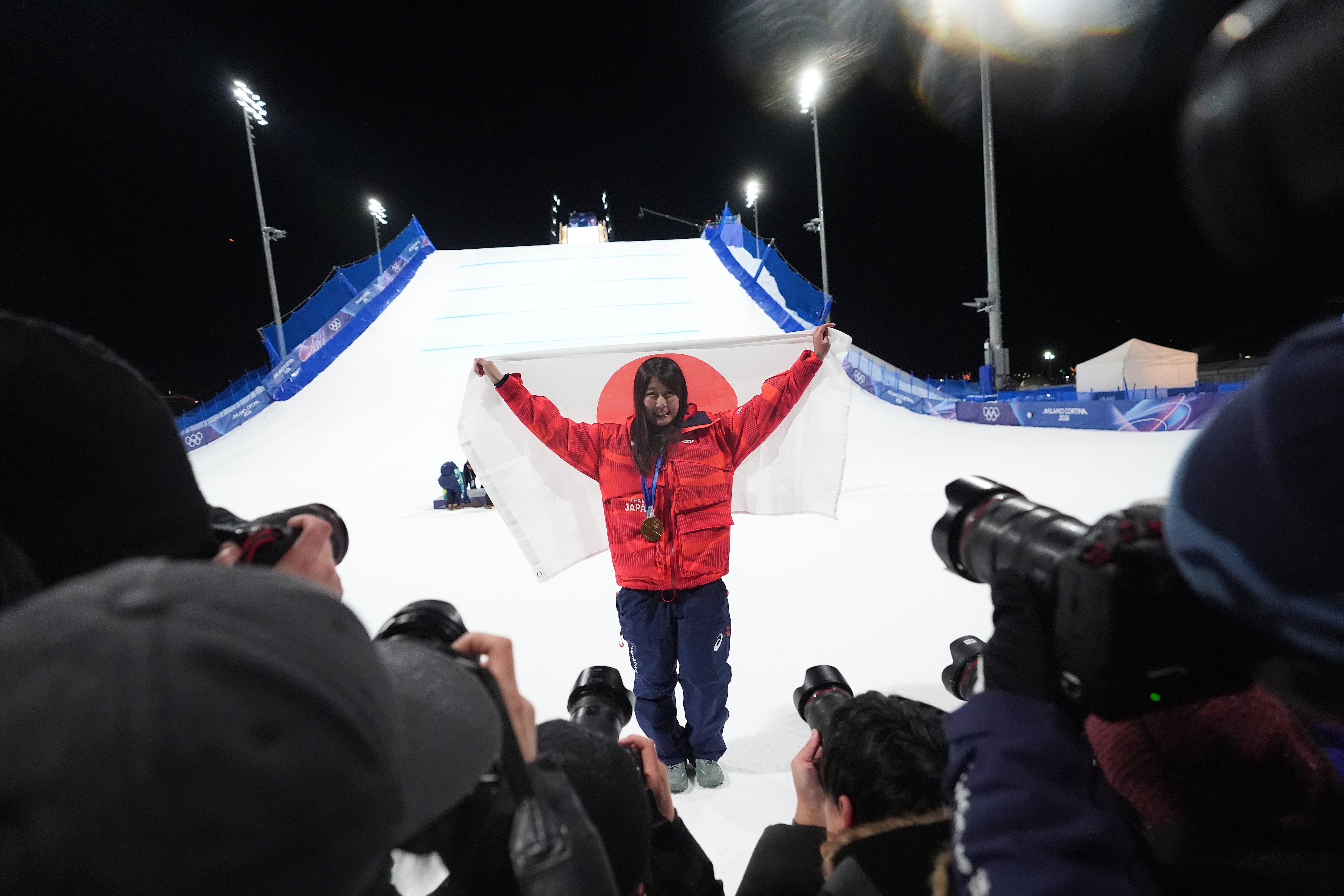 La japonesa Kokomo Murase, medallista de oro, sostiene una bandera de Japón tras ganar la final femenina de snowboard big air en los Juegos Olímpicos de Invierno de 2026 (AP)