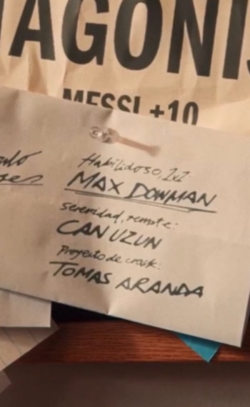 Una nota de papel fijada con una chincheta muestra nombres manuscritos sobre un fondo con el texto MESSI +10